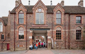 Families leaving Jackfield Tile Museum, a historical red brick building.