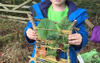 Little boy showing he nature collage made of natural objects