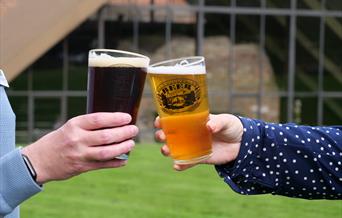 Two hands holding two glasses of beer.