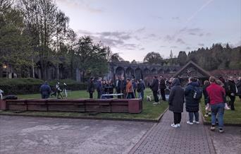 A photo of everyone gathering up to see the stars through a telescope.