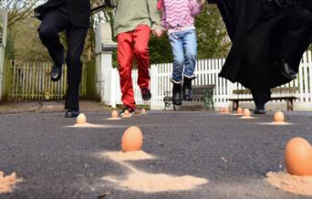 A group of four, shown from the waist down taking part in Victorian egg dancing.