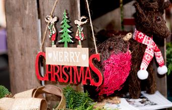 A wooden Merry Christmas sign is shown on a craft stall