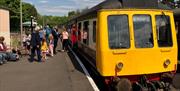The Class 108 Diesel Multiple Unit at Spring Village station. The platform has lots of customers on waiting to board.