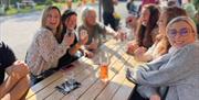 A group of woman sat at a pub bench enjoying a drink