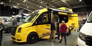 A yellow and black VW camper shown at a previous show