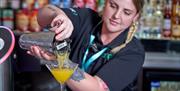 A bartender pouring a cocktail