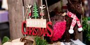 A wooden Merry Christmas sign is shown on a craft stall