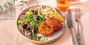 Wildwood Restaurants' smoked salmon & haddock fish cakes on a plate with a glass of wine.