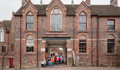 Families leaving Jackfield Tile Museum, a historical red brick building.