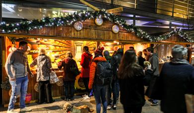 Visitors of Telford Christmas Market queuing up to buy good from a wooden chalet.