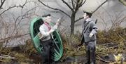 A diorama showing a good natured argument between a coracle man and a landowner about fishing.