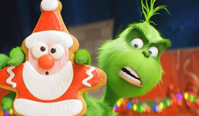 An image from The Grinch movie of The Grinch holding a Christmas cookie