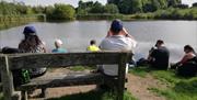 People sat on a bench overlooking a pool of water near Little Wenlock