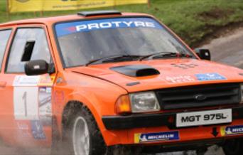 An orange vintage ford rally car pictured,