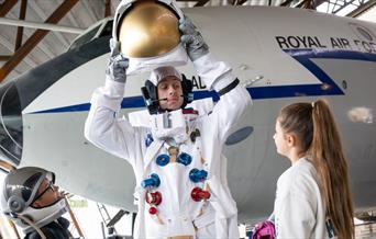 Young visitors to RAF Museum Midlands speaking with a man dressed as an astronaut.