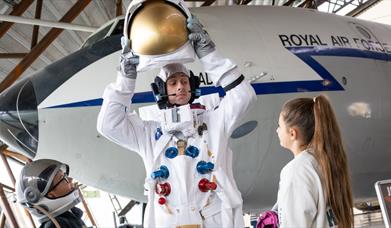 Young visitors to RAF Museum Midlands speaking with a man dressed as an astronaut.