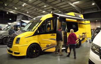 A yellow and black VW camper shown at a previous show