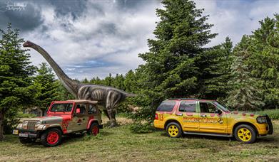 Ranger vehicles and dinosaur shown in the grounds