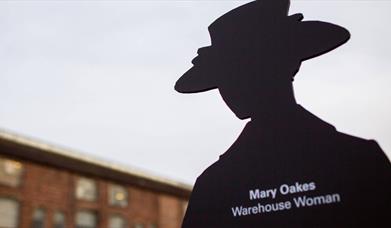 A black cut out of a woman in a hat, white text on it reads Mary Oakes Warehouse woman.