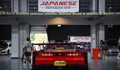 A photo from the inside of a previous show showing visitors and a red performance Honda on display