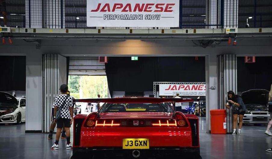 A photo from the inside of a previous show showing visitors and a red performance Honda on display