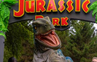A velociraptor pictured in front of the Jurassic park gate.