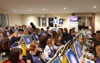 a sip and paint class taking part in an event