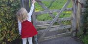 A little girl opening a gate in the countryside in Telford.