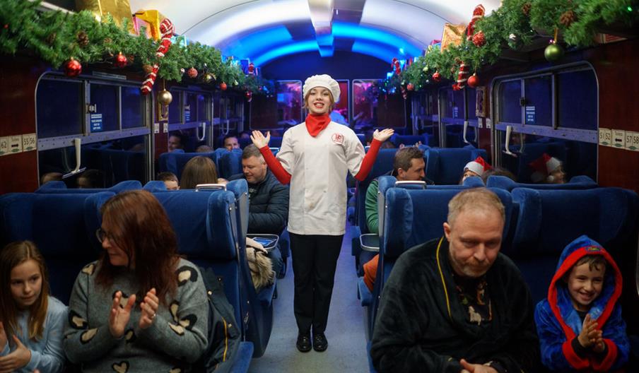 Female Chef in Train Carriage surrounded by customers sat down