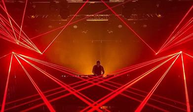 DJ in DJ Booth with red lasers surrounding him