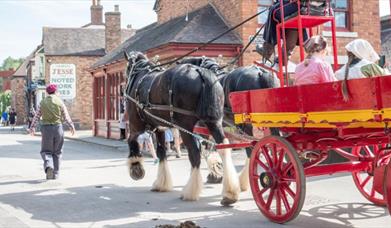 Two shire horses are pictured pulling a passenger cart through the streets of Blists Hill Victorian Town