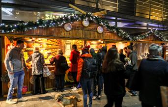 Visitors of Telford Christmas Market queuing up to buy good from a wooden chalet.