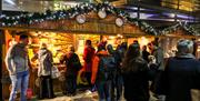 Visitors of Telford Christmas Market queuing up to buy good from a wooden chalet.