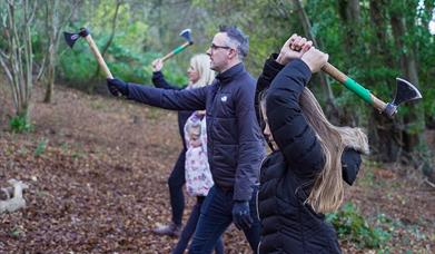 A family of four participating in axe throwing