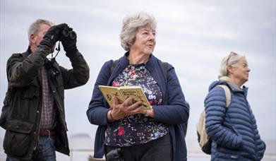 Photograph of people outside, bird watching.