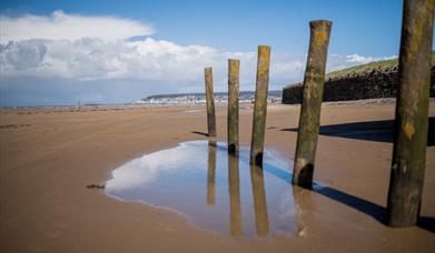 Photograph of Uphill beach with sand dunes in distance and a blue sky.