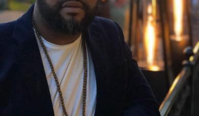 Photograph of Eleazar stood in front of a bar