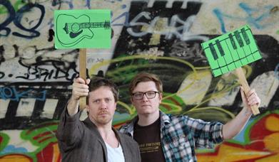Gavin and John - musicians - holding up green musical placards
