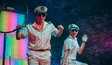 Two men on stage wearing uniforms associated with ship captains