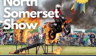 A motorbike stunt rider riding through a flaming arch on a poster advertising the North Somerset Show