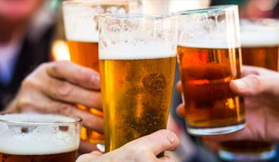 Close up of hands holding three pints of beer