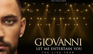 Gionvanni facing the camera with spotlights behind hm.