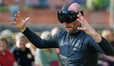 A man all in black wearing a huge black goggle headset on his face