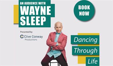 Wayne Sleep in pink jacket sitting on a barstool