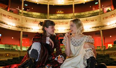 2 female performers sat on stage eating