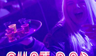 A lady in a nightclub holding a tray of shots