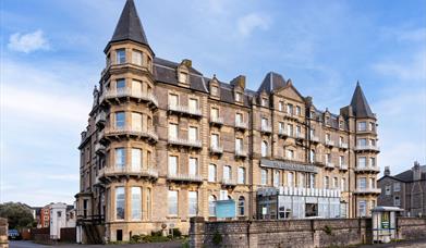 Exterior of a big four-storey hotel with turrets on the corners