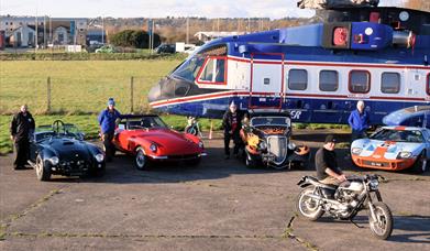 Vintage cars and an old helicopter on display at the Weston-super-Mare Helicopter Museum