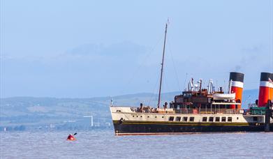 A kayaker looks tiny up against the Waverley Paddle Steamer in the Bristol Channel