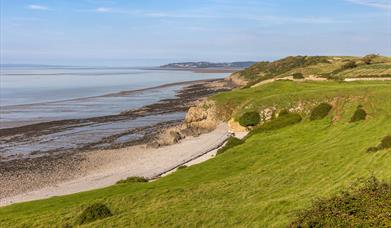 A green field looking down onto a shingle beach